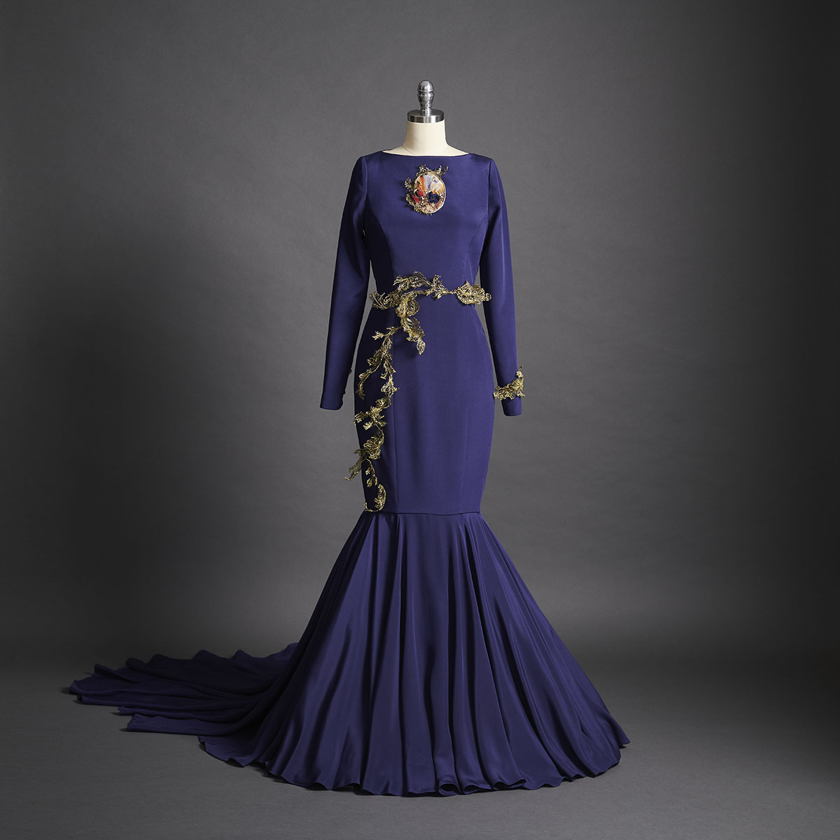 A navy blue crepe de chine dress featuring a sweeping fishtail train. The embroidery, a combination of golden French lace and wire, delicately wraps around the waistline of the dress. - DELPHINE GENIN