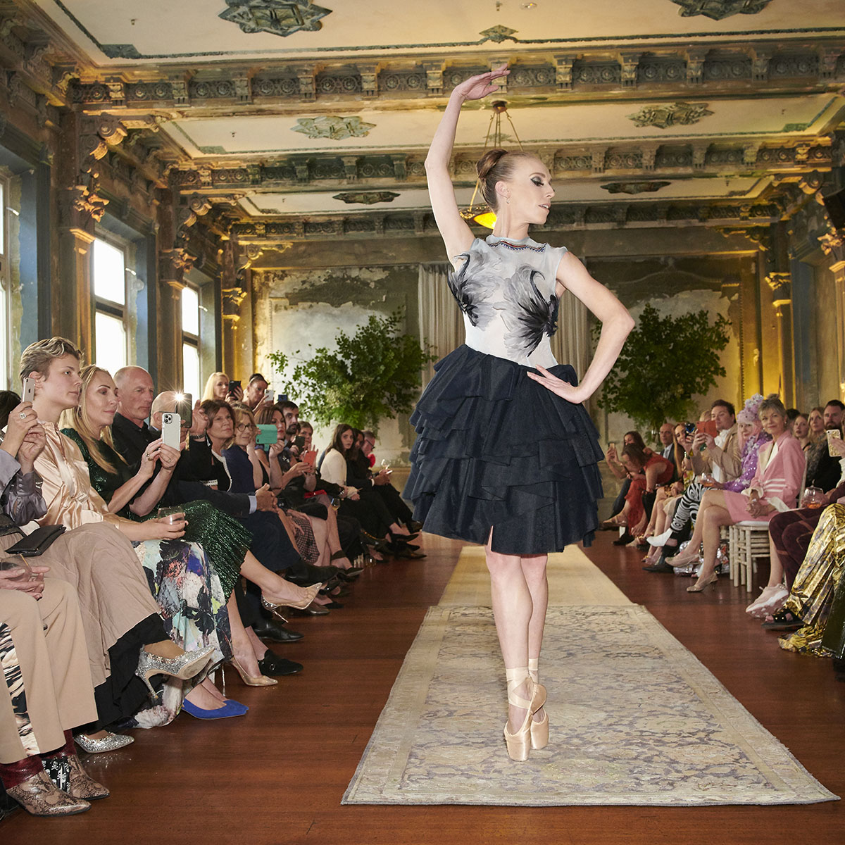 Two hand-embroidered sphinges with multifaceted seed beads appear facing each other on the back of the light blue silk organza bodice that is supported by a navy blue tutu made out of 17 layers of Italian soft tulle. On the front of the dress, a mixture of natural and hand-dyed goose feather create the illusion of a flying eagle. - DELPHINE GENIN